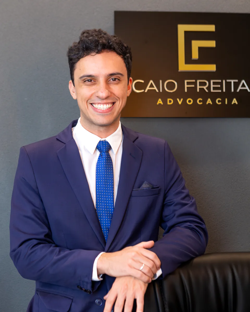 Dr. Caio Freitas em seu escritório, ao lado da placa da Caio Freitas Advocacia